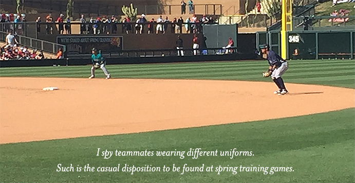 Teammates on field wearing different uniforms during spring training